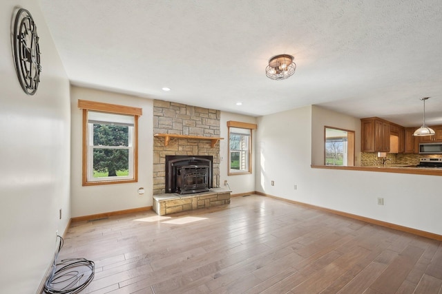 unfurnished living room with light wood-style floors, baseboards, and a healthy amount of sunlight
