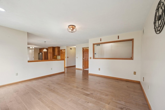 unfurnished living room featuring light wood finished floors, visible vents, and baseboards