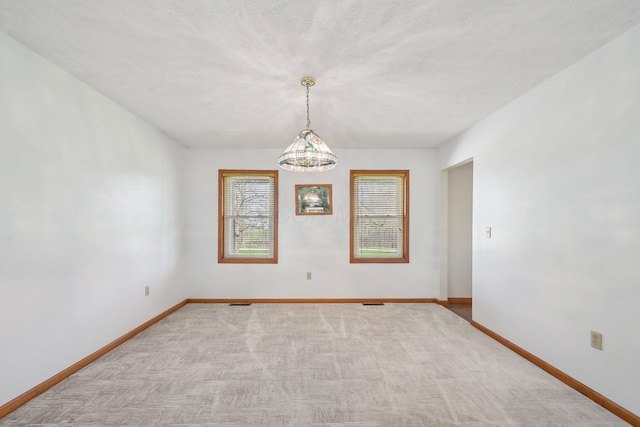 spare room featuring light carpet and baseboards