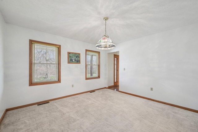 carpeted empty room with a chandelier, baseboards, and visible vents