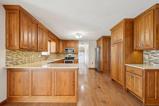 kitchen with brown cabinetry, a peninsula, and stainless steel appliances