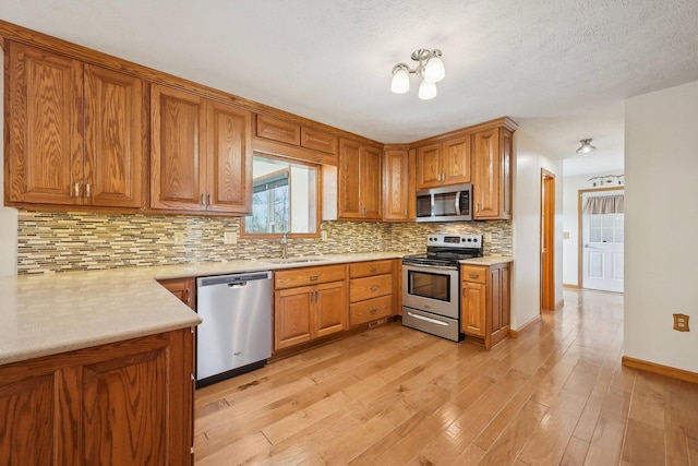 kitchen featuring brown cabinetry, appliances with stainless steel finishes, and light wood finished floors