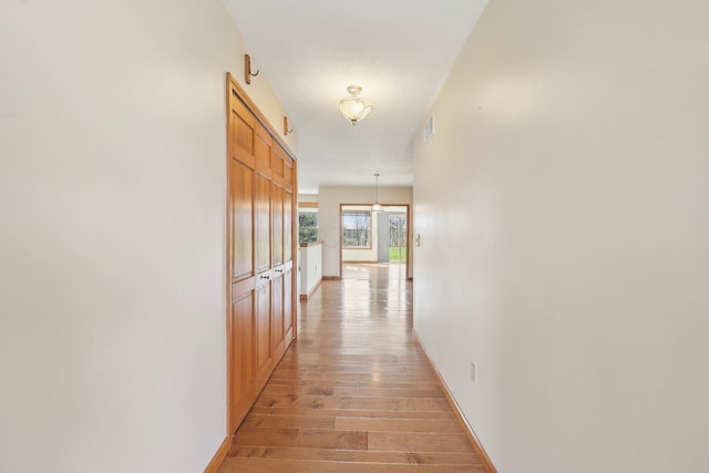 hall featuring light wood-style flooring and baseboards