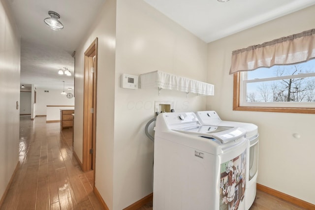 laundry room with light wood-style flooring, washing machine and dryer, laundry area, and baseboards