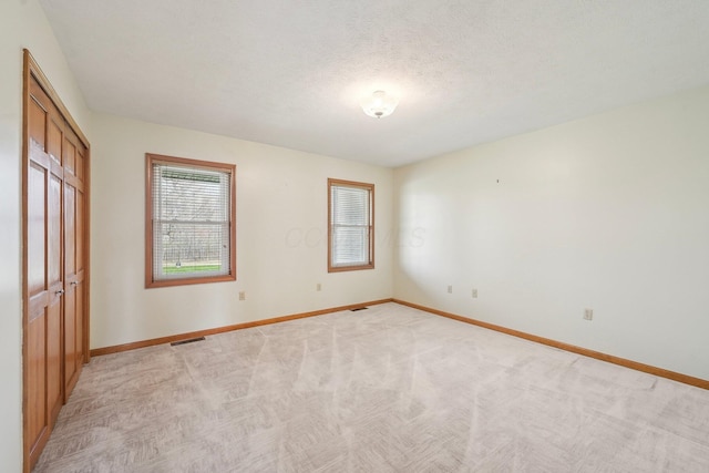 unfurnished bedroom with light carpet, baseboards, visible vents, and a textured ceiling