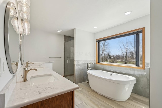 bathroom featuring a sink, tile walls, a soaking tub, double vanity, and a stall shower