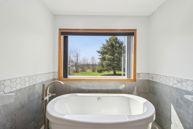 full bathroom with tile walls, a soaking tub, and wainscoting