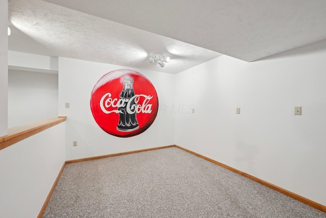 spare room featuring carpet flooring, a textured ceiling, and baseboards