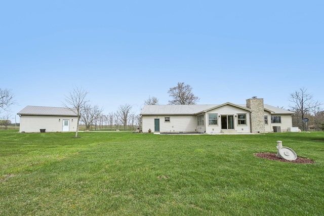 back of property featuring a patio, a chimney, metal roof, and a lawn