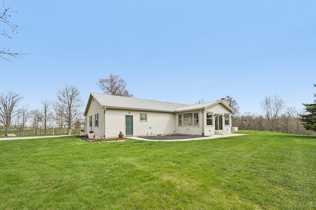 back of house featuring entry steps, a yard, and metal roof
