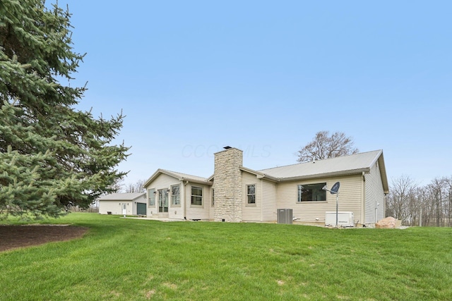 rear view of house with central AC, a yard, metal roof, and a chimney