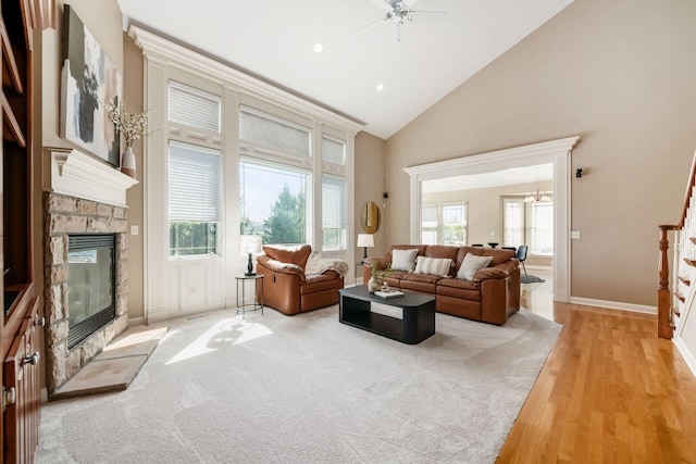 4568 Hickory Rock Dr, Powell, OH 43065 - living room featuring baseboards, light wood finished floors, high vaulted ceiling, a stone fireplace, and ceiling fan with notable chandelier