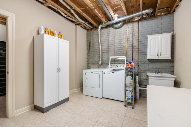 4568 Hickory Rock Dr, Powell, OH 43065 - laundry room with light tile patterned floors, cabinet space, brick wall, and washer and clothes dryer