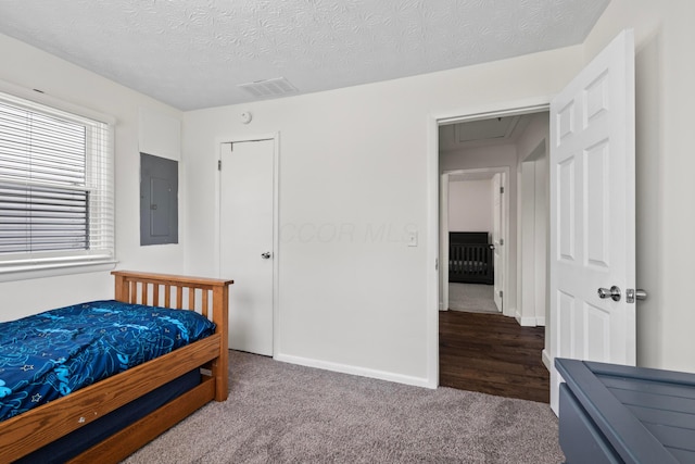 bedroom with carpet, a textured ceiling, visible vents, electric panel, and attic access