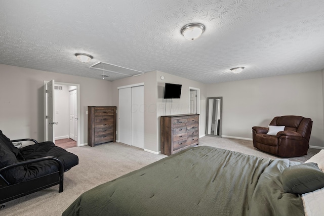 carpeted bedroom with baseboards, a closet, attic access, and a textured ceiling