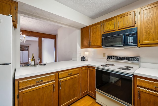 kitchen with white appliances, light countertops, brown cabinetry, and a textured ceiling