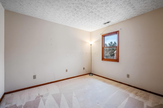 carpeted spare room featuring baseboards, visible vents, and a textured ceiling