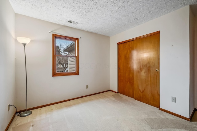 unfurnished bedroom featuring carpet, baseboards, and a textured ceiling