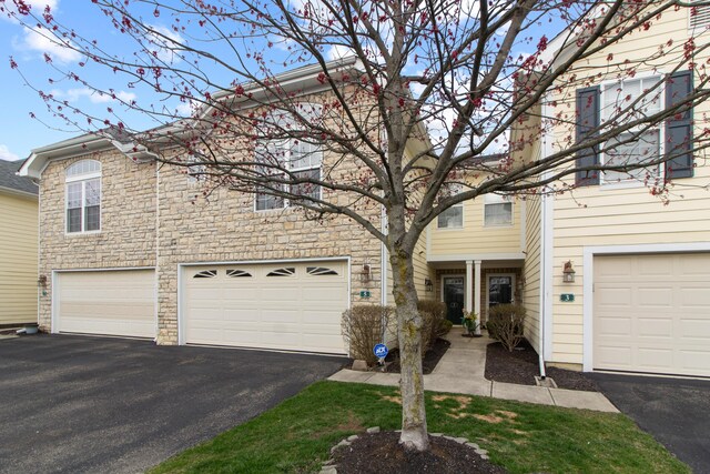 multi unit property featuring stone siding, a garage, and aphalt driveway