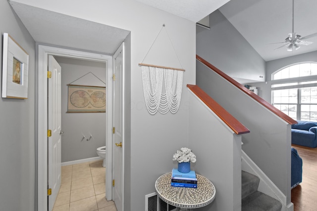 staircase featuring baseboards, a ceiling fan, and tile patterned flooring
