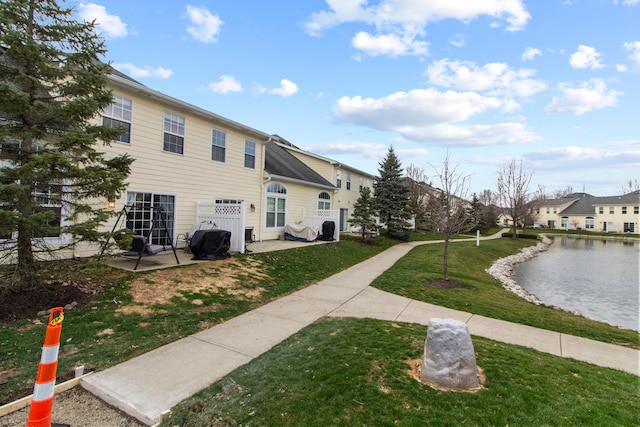 exterior space featuring a water view, a patio, and a lawn