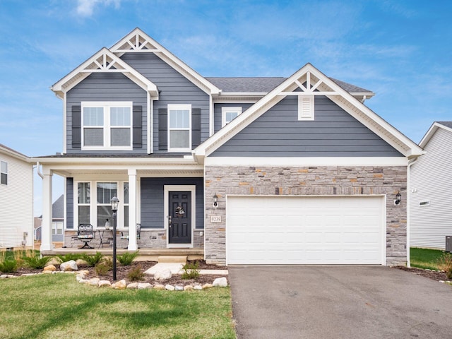 9239 Horseshoe St, Plain City, OH 43064 - craftsman house featuring driveway, a garage, stone siding, and a porch