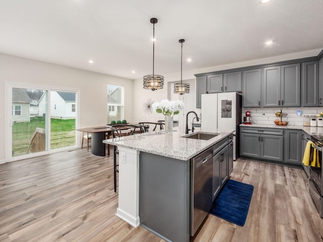 9239 Horseshoe St, Plain City, OH 43064 - kitchen with light wood finished floors, appliances with stainless steel finishes, an island with sink, a sink, and a breakfast bar area