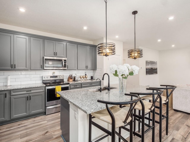 9239 Horseshoe St, Plain City, OH 43064 - kitchen with backsplash, a sink, gray cabinetry, stainless steel appliances, and light wood-style floors