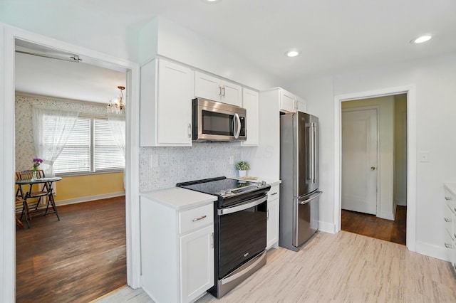 1800 Timberline Dr, Springfield, OH 45504 - kitchen featuring an inviting chandelier, light countertops, white cabinetry, light wood-style flooring, and appliances with stainless steel finishes