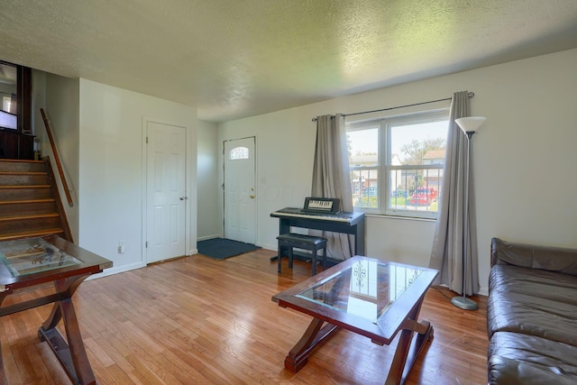 1473 Venice Dr, Columbus, OH 43207 - living room featuring light wood-type flooring, baseboards, a textured ceiling, and stairs