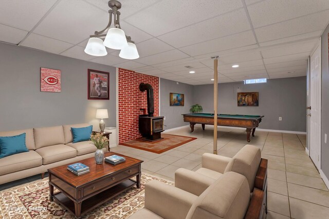 living room featuring light tile patterned floors, a drop ceiling, and baseboards