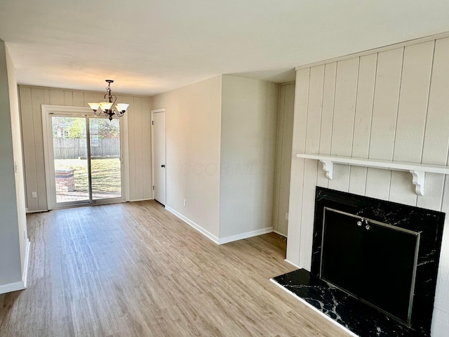 unfurnished living room with light wood finished floors, baseboards, a notable chandelier, and a tile fireplace