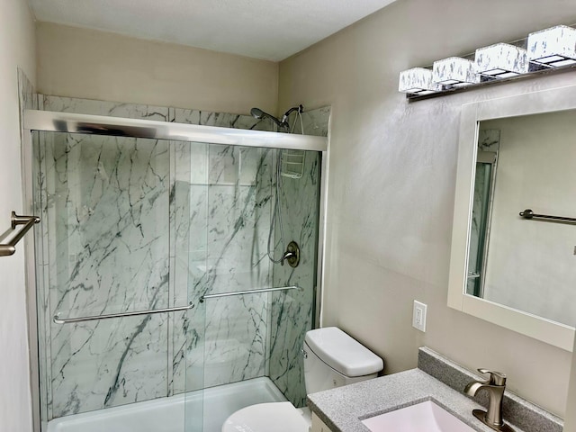 bathroom featuring toilet, vanity, and a marble finish shower