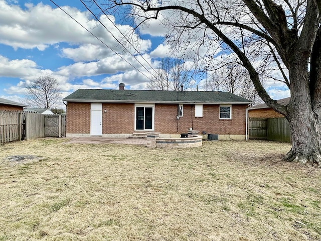 back of house featuring a fenced backyard, brick siding, a lawn, and a patio