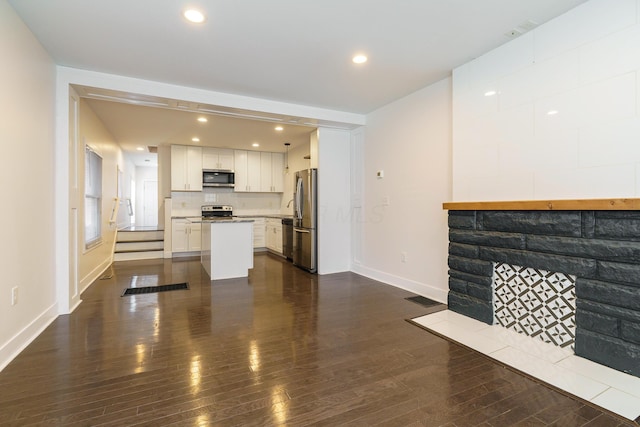 unfurnished living room featuring dark wood-type flooring, visible vents, baseboards, and recessed lighting