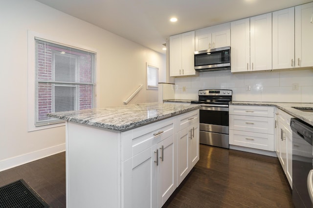 kitchen featuring a center island, appliances with stainless steel finishes, light stone counters, and white cabinetry