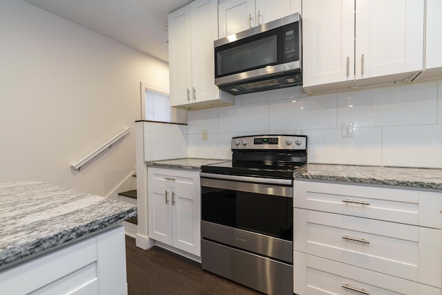 kitchen with light stone counters, dark wood-type flooring, decorative backsplash, appliances with stainless steel finishes, and white cabinetry