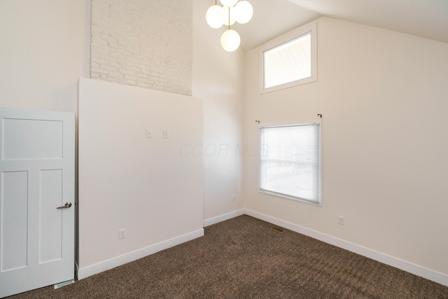 unfurnished room featuring dark colored carpet, lofted ceiling, and baseboards