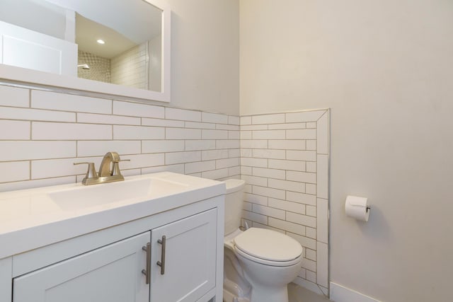 bathroom featuring toilet, vanity, and tile walls