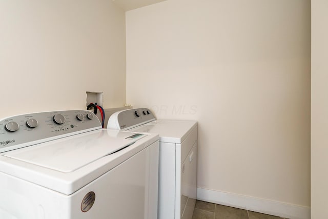 washroom with light tile patterned floors, baseboards, washer and dryer, and laundry area