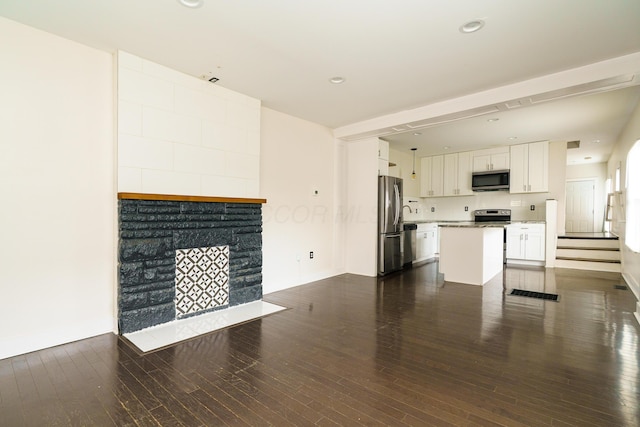 unfurnished living room with dark wood-style floors, a fireplace with flush hearth, baseboards, visible vents, and recessed lighting
