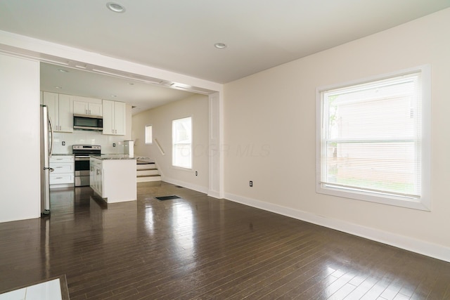 unfurnished living room featuring dark wood-type flooring, baseboards, stairs, and recessed lighting