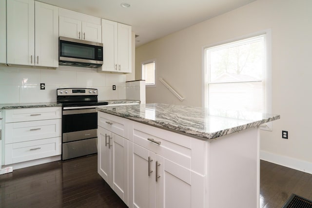 kitchen with light stone countertops, dark wood-type flooring, backsplash, and appliances with stainless steel finishes
