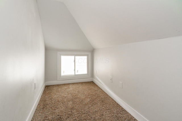additional living space with light carpet, vaulted ceiling, and baseboards
