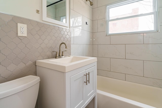 full bathroom featuring tile walls, toilet, vanity, and bathing tub / shower combination