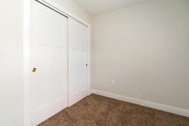 unfurnished bedroom featuring baseboards, carpet, and a closet