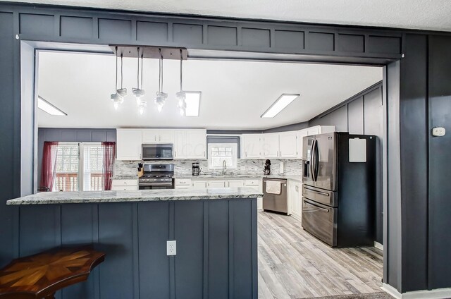 kitchen featuring white cabinets, a kitchen bar, tasteful backsplash, and appliances with stainless steel finishes