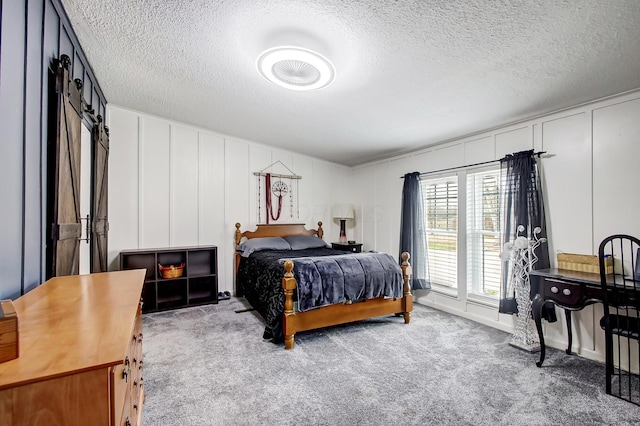 bedroom featuring a decorative wall, carpet flooring, and a textured ceiling