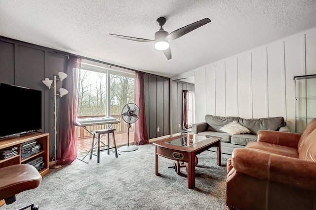 carpeted living area featuring a decorative wall, a textured ceiling, and ceiling fan