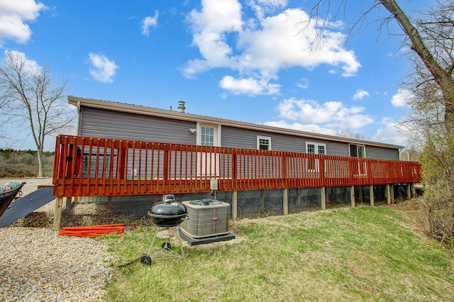 rear view of property with a lawn, central air condition unit, and a wooden deck